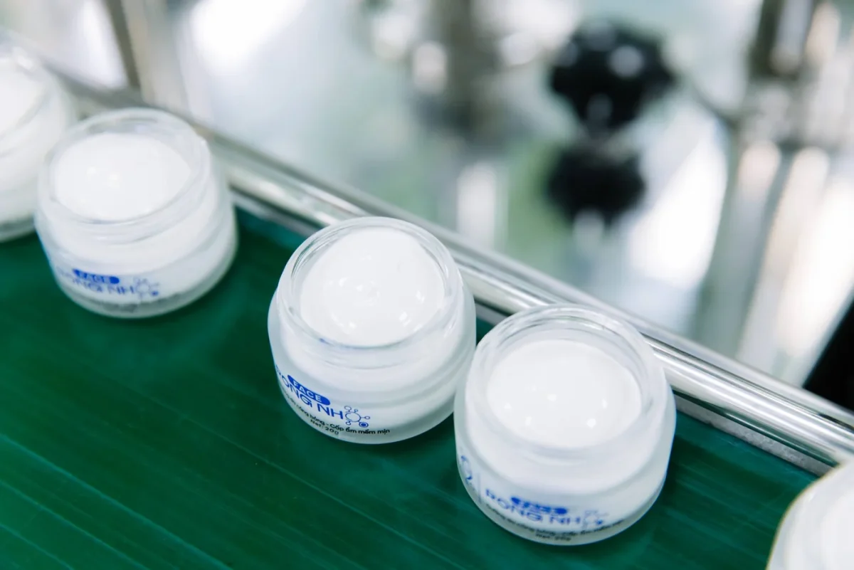 Các hũ kem mở nắp trên băng chuyền chiết rót
