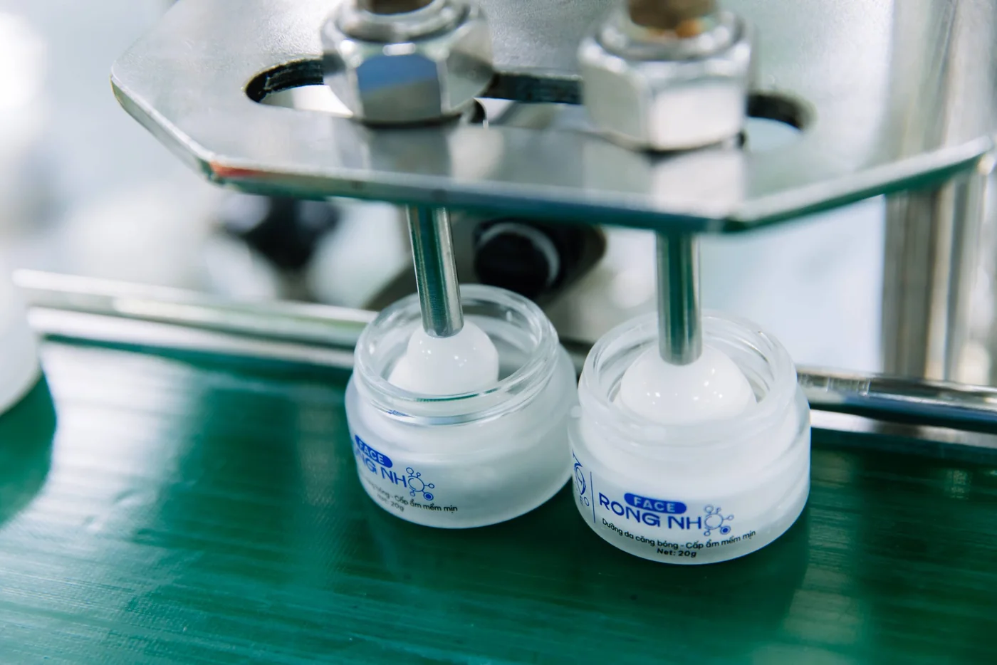 Mẫu thử và lô sản xuất đầu tiên: những điểm cần đối chiếu 2 Đầu chiết rót đang đưa kem vào các hũ trên băng chuyền